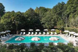 a swimming pool with umbrellas and lounge chairs at Les Prés d'Eugénie in Eugénie-les-Bains