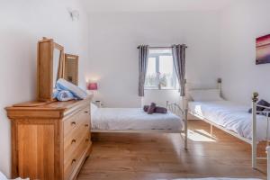 a bedroom with two beds and a dresser and a mirror at Pembrokeshire Near Beach With A Hot Tub in Pembroke