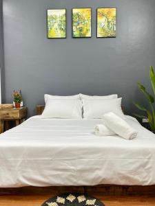 - un lit blanc avec 4 photos sur le mur dans l'établissement The Little Ha Noi 5 Bedrooms Large Yard Balcony, à Hanoï