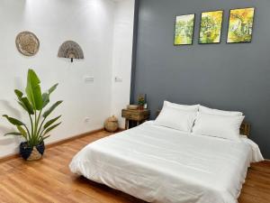 - une chambre avec un lit blanc et une plante en pot dans l'établissement The Little Ha Noi 5 Bedrooms Large Yard Balcony, à Hanoï 49 autres photos