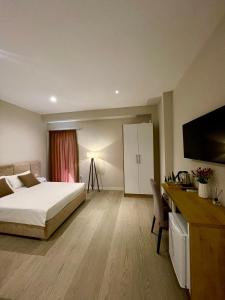 a bedroom with a bed and a desk and a television at Solea Hotel in Vlorë +41 photos