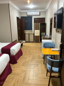 a room with two beds and a table and a kitchen at اجنحه البيداء البخاري1 in Al Madinah