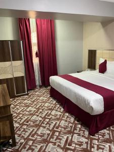 a hotel room with two beds and red curtains at اجنحه البيداء البخاري1 in Al Madinah +70 photos