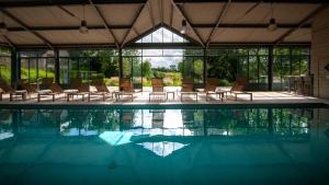 a swimming pool with chairs and a table and windows at Le Clos de Grâce in Honfleur