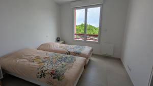 two beds in a room with a window at Cocon moderne avec terrasse a deux pas de locean in Saint-Brevin-les-Pins