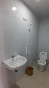 a white bathroom with a sink and a toilet at Madak ekas homestay 2 in Ekas