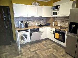 a kitchen with white cabinets and a washer and dryer at Gnezdo Apartment Sarafovo in Burgas City