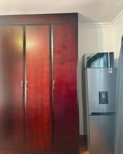 a pair of wooden cabinets next to a refrigerator at Tsheryl's Guesthouse in Centurion