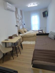 una camera d'albergo con 2 letti, un tavolo e una scrivania di Pogácsás II Apartman Tokaj a Tokaj