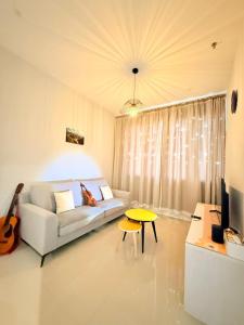 sala de estar con sofá blanco y guitarra en Iconic Regency Service Residences - Bee's Home, en Bayan Lepas