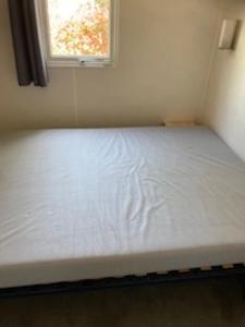 a bed in a small room with a window at Bonne Anse plage 411 mobile home 3 chambres in Les Mathes +2 photos
