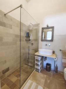 een badkamer met een glazen douche en een wastafel bij Trullo il Querciolo in Ostuni