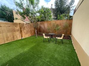 un patio con 2 sillas y una mesa en el patio trasero en 2-Appartement RDC 28 m2 avec Jardin, en Mantes-la-Jolie