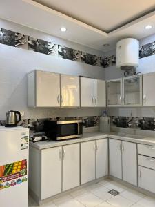 a kitchen with white cabinets and a microwave at شقق الزهور - العزيزية in AlUla