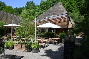 an outdoor restaurant with tables and umbrellas and chairs at Bosgeluk Durbuy in Durbuy