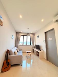 sala de estar con sofá y guitarra en Iconic Regency Service Residences - Bee's Home, en Bayan Lepas