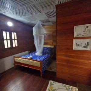 ein Zimmer mit einem Bett in einem Zimmer mit Holzwänden in der Unterkunft Mionga in Santa Cruz