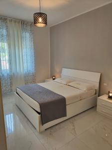 a white bedroom with a large bed and a chandelier at Alloggio comodo a Rapallo - Vicino al Mare in Rapallo