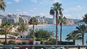 uitzicht op een strand met palmbomen en gebouwen bij Magic holiday - 1st line, seaview, pool & parking in Ifach