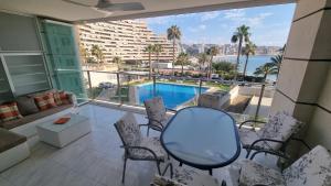 een balkon met een tafel en stoelen en een zwembad bij Magic holiday - 1st line, seaview, pool & parking in Ifach