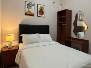 a bedroom with a bed and a lamp and pictures on the wall at Villa Ostara Kota Batu in Batu
