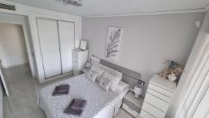 een witte slaapkamer met een bed en een ladekast bij Magic holiday - 1st line, seaview, pool & parking in Ifach +10 foto's