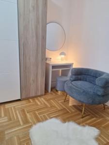 a living room with a blue chair and a mirror at Seaview apartman Vice in Trogir