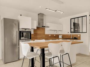 a kitchen with a wooden table and white chairs at Nouvelle Villa Harmonia Piscine Proche Montpellier et Plages in Saint-Jean-de-Védas