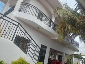 a white house with black railings and a balcony at Sukuta nema guest house in Sareh Mowndeh