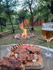 a grill with meat and a glass of wine at CABANE Nadejda SPERANTA in Găgeni