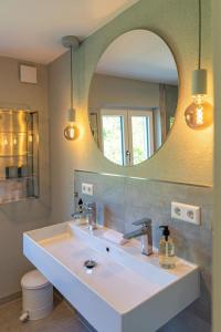 un bagno con un lavandino bianco e uno specchio di Freistehendes Ferienhaus mit Kamin, Sauna, atemberaubenden Blick ins Tal, mehrere Terrassen, 1500qm Grundstück 1,6m hoch eingezäunt a Gerabronn
