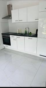 a white kitchen with white cabinets and a stove at Villa Lakeview Appartment in Leissigen