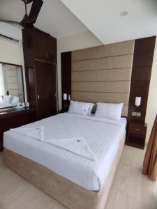 a large white bed in a bedroom with a mirror at White Park Hotel & Suites in Chittagong