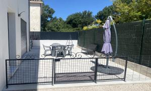 a gate with a table and an umbrella on a patio at Joli bas de Villa in Peypin