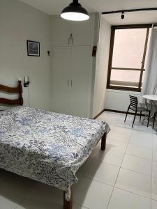 a bedroom with a bed and a table and a window at studio aconchegante para 02 na praia de Amaralina in Salvador