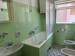 a green bathroom with a tub and a sink and a toilet at Hostel Guesthouse Mira in Omiš
