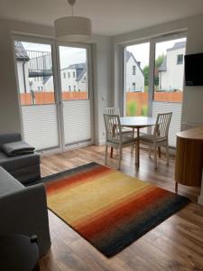 sala de estar con mesa, sillas y alfombra en Seaside Apartment, en Trzęsacz