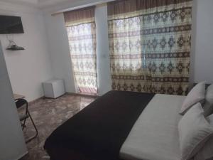 a bedroom with a large bed and two windows at Sukuta nema guest house in Sareh Mowndeh
