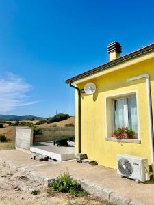 a yellow house with a window and a microwave at San Leonardo Country House in Calangianus