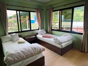 a bedroom with two beds and windows with a view at Niru Yoga Homestay sound healing & hiking retreat in Bhaktapur
