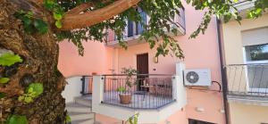 a pink building with a gate next to a tree at Ai Gelsi in Mortegliano