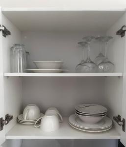 a white cabinet with plates and bowls and glasses at Exclusivo Departamento! in Cochabamba