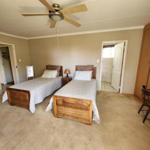 a bedroom with two beds and a ceiling fan at Simply Rooted Cottage in Piet Retief
