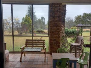 a porch with a bench and a table and chairs at Simply Rooted Cottage in Piet Retief