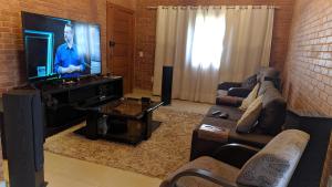 ein Wohnzimmer mit Couch und Flachbildfernseher in der Unterkunft Casa ao lado da cervejaria 3 Santas no Caravaggio in Santa Teresa