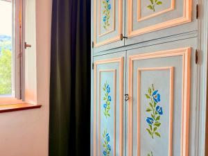 a wooden cabinet with blue flowers on it next to a window at Castellino di Castello di fiemme in Castello di Fiemme
