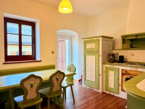 a kitchen with green cabinets and a table and chairs at Castellino di Castello di fiemme in Castello di Fiemme
