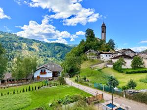 a small village with a church and a grassy hill at Castellino di Castello di fiemme in Castello di Fiemme