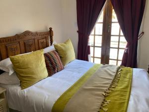 a bed with yellow and green pillows and a window at Mi casa guesthouse in Gaborone +60 photos