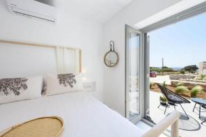 a white bedroom with a large bed and a balcony at Fos Residence Dryos in Drios
